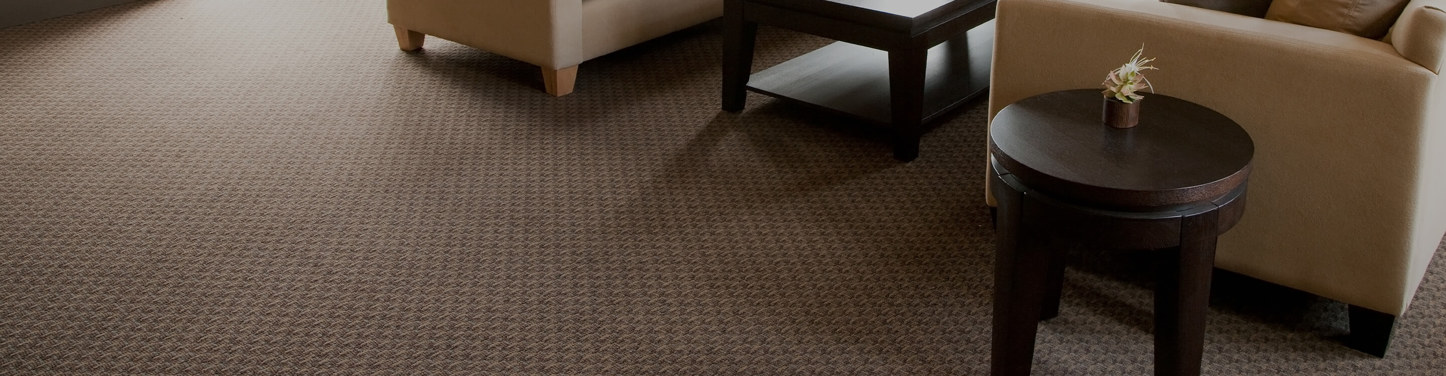 neutral carpet flooring A warm living room with patterned carpet and tan furniture.